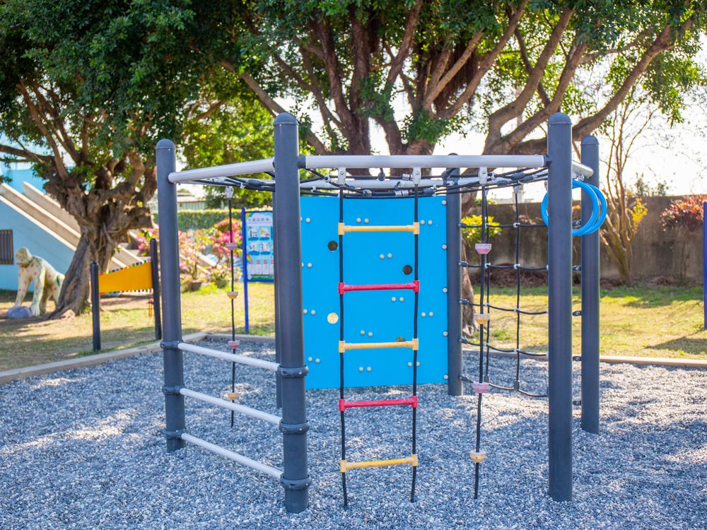 興華國小樹蔭下的攀爬架與彩色繩梯 A climbing frame with a colorful rope ladder in the shade at SingHua