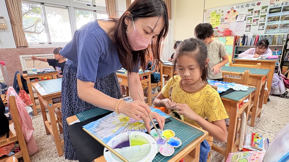 興華國小老師彎腰指導學生畫畫 A SingHua teacher leaning in to help a student with a painting