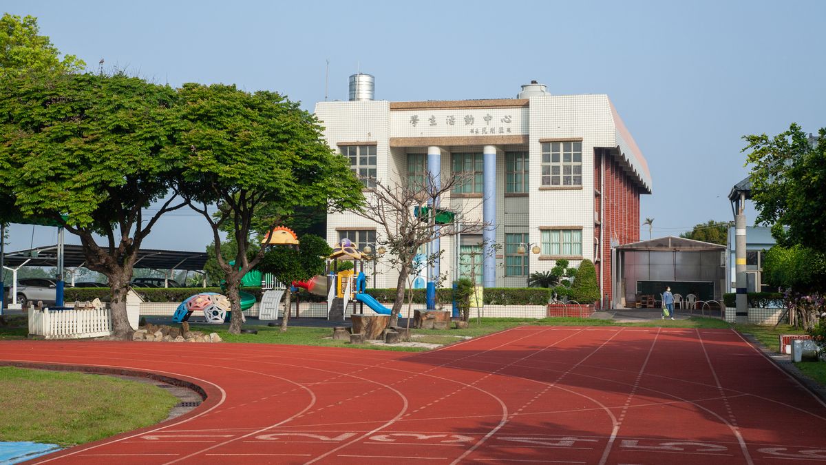 興華國小的紅色跑道，後方是學生活動中心與大樹 SingHua's red running track, with the Student Activity Center and big trees behind it