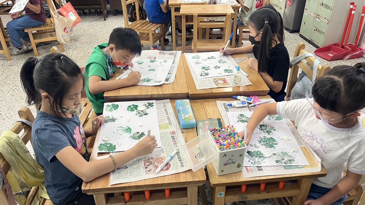 興華國小學生在教室裡，用綠色顏料創作葉子圖案的作品 SingHua students at their desks, creating artwork full of green leaf patterns