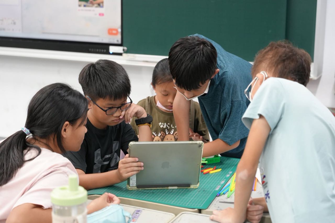 學生圍著平板一起討論互動遊戲