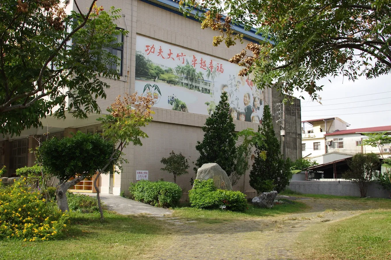 Tachu's entrance garden with a mural reading Kung Fu Tachu, Outstanding and Happy 大竹國小校園花園與「功夫大竹 卓越幸福」壁畫