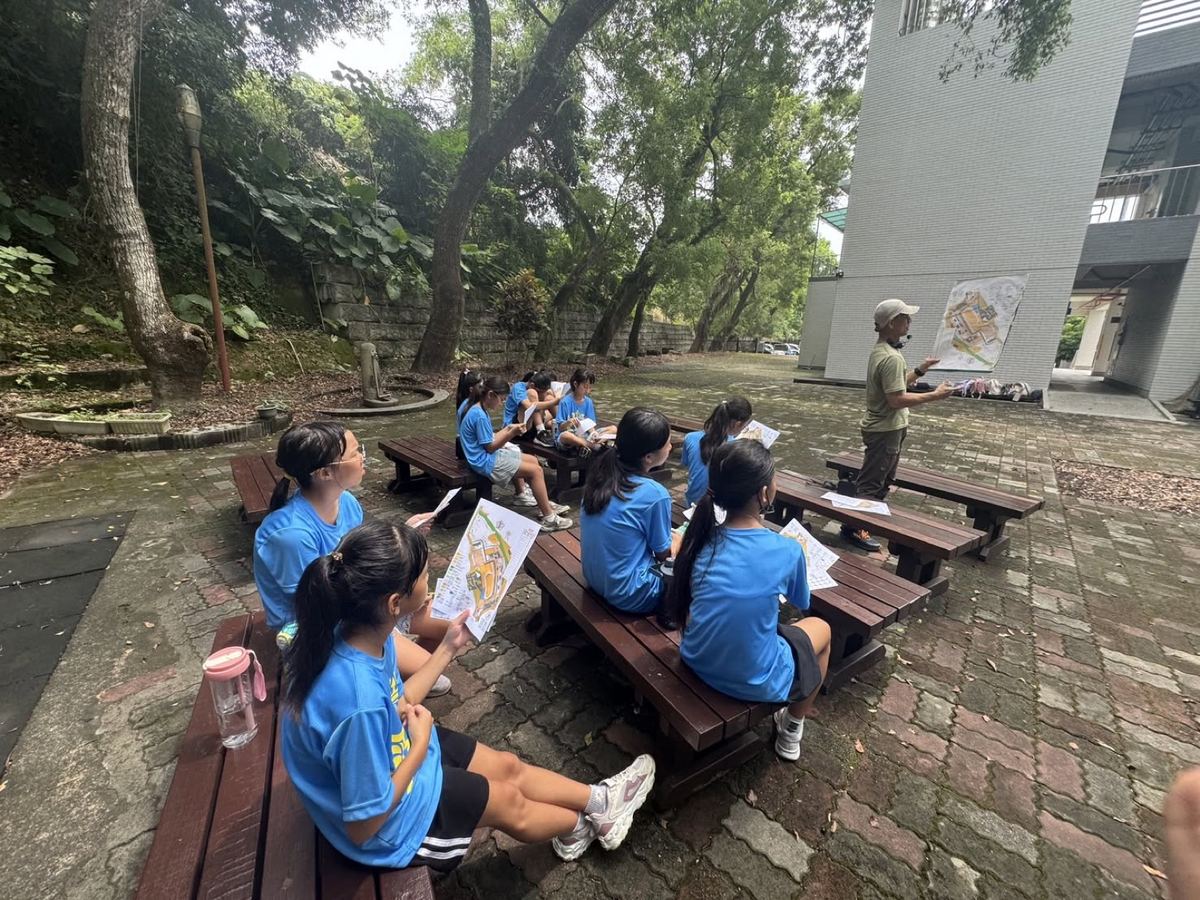 Tachu students sitting outdoors listening to a campus safety briefing with a map 大竹學生戶外聽取校園安全簡報