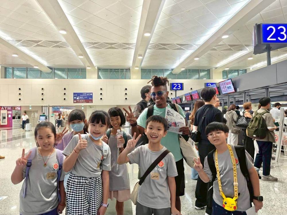 田中國小學生完成英語訪談後與外國旅客在機場報到櫃檯前合影