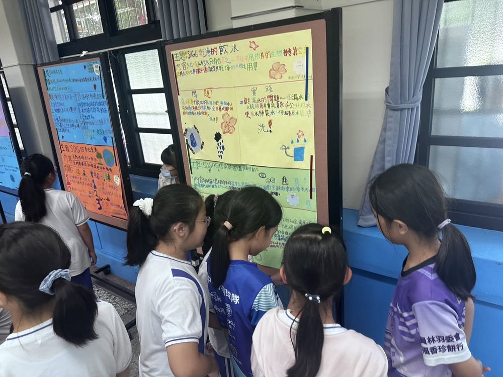田中國小學生圍看同學手繪的 SDG6 乾淨飲水與 SDG13 氣候行動主題海報