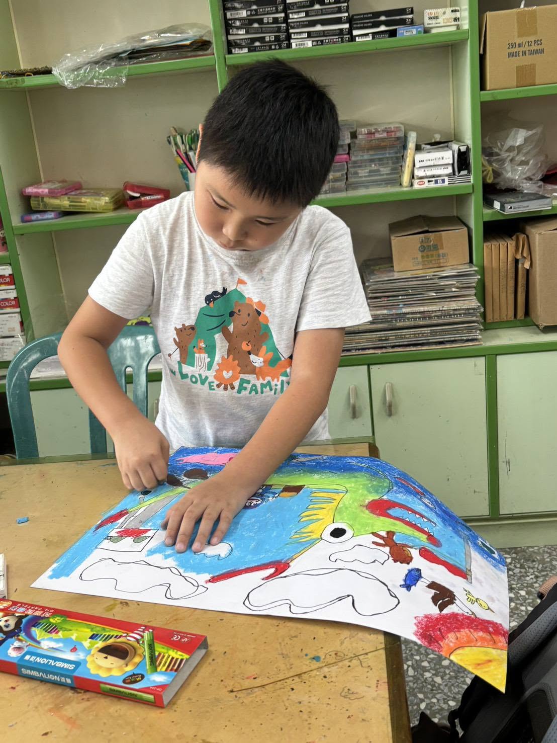 A Tiantou student colouring a large dragon-boat drawing