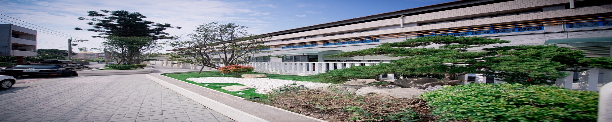 The front courtyard of Wansing Elementary School with white balustrades, manicured gardens and the main teaching building behind