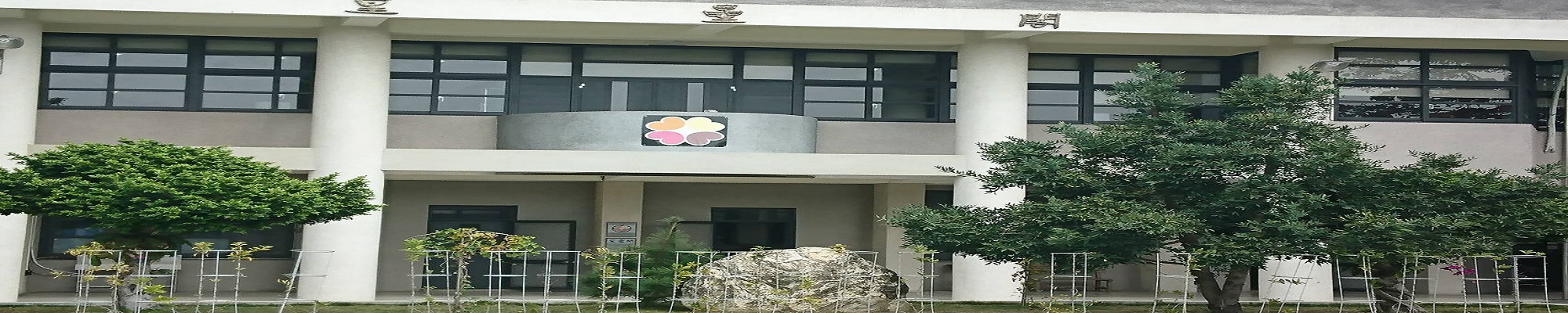 Front facade of the Wansing main teaching building, with the school's plum-blossom emblem on the second-floor balcony wall