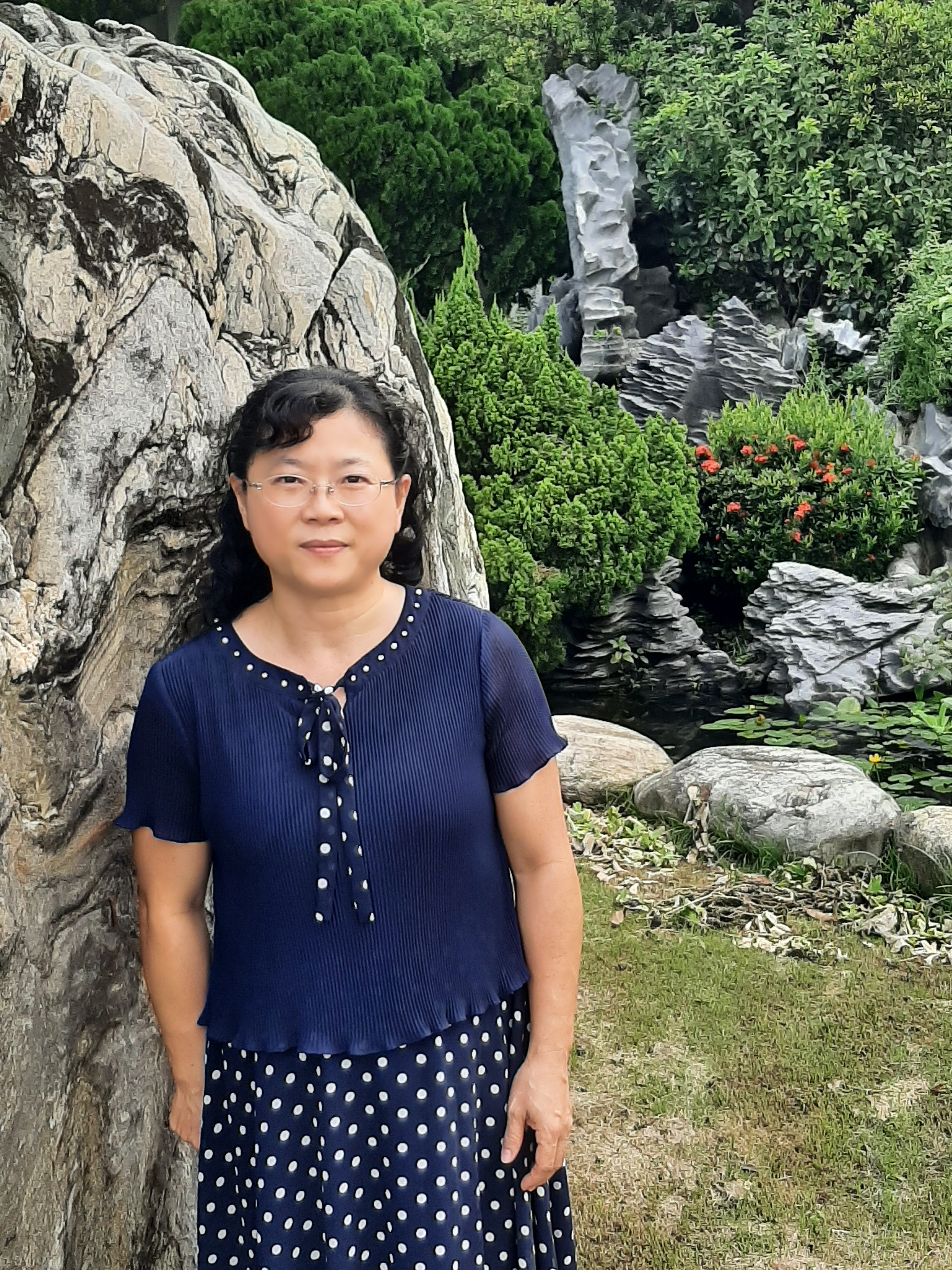 Principal Wu Kuei-chih of Wansing Elementary School, standing in front of a stone garden waterfall