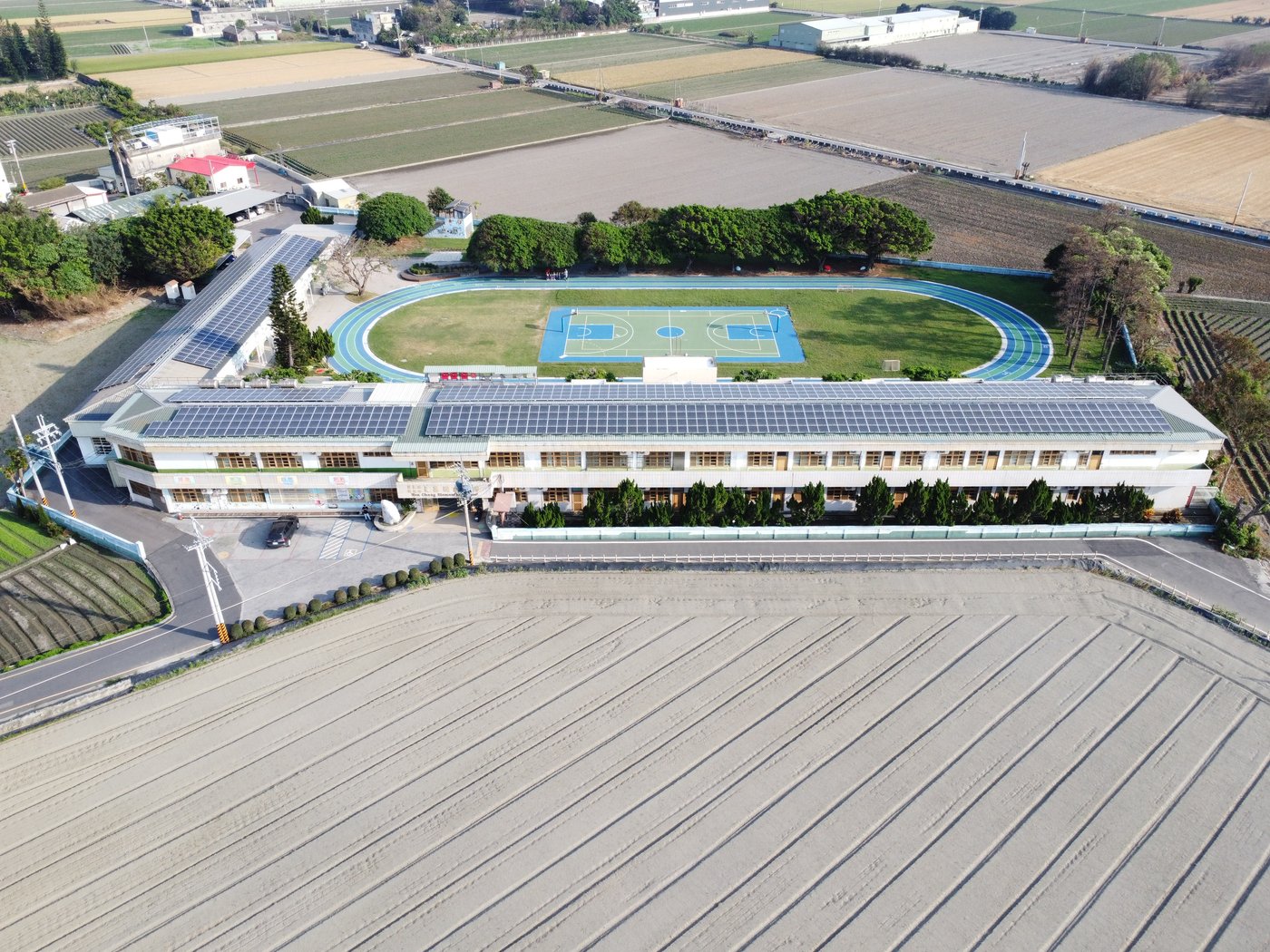 Wide aerial view of Wenchang Elementary School campus and surrounding farmland