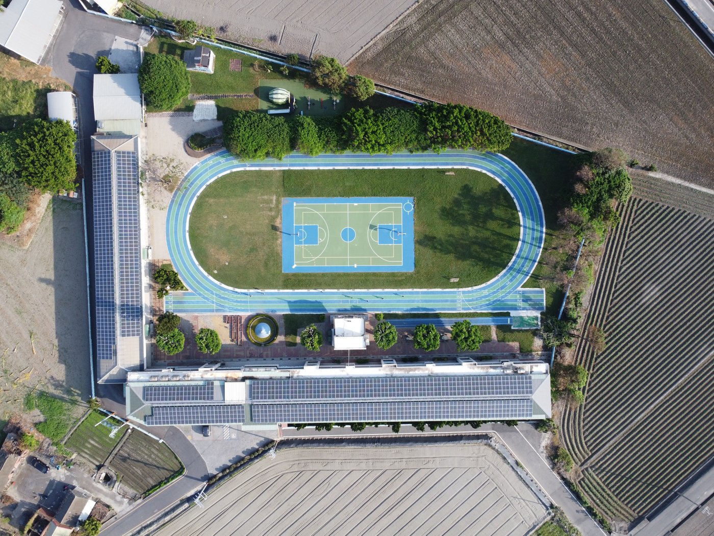 Top-down aerial view of Wenchang campus showing the blue running track and basketball court