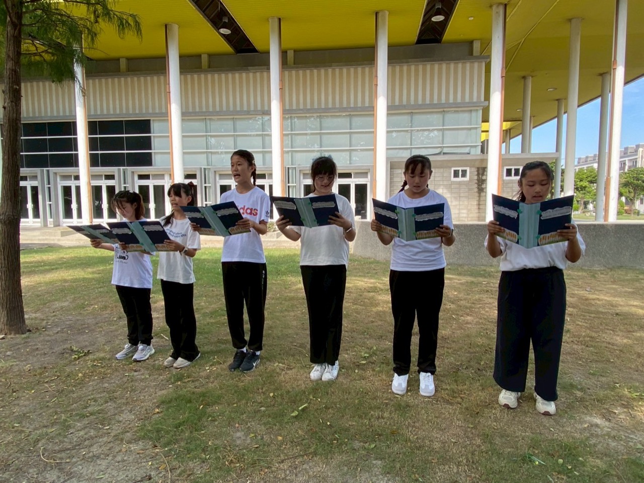 Students reading aloud at an English recitation contest outdoors