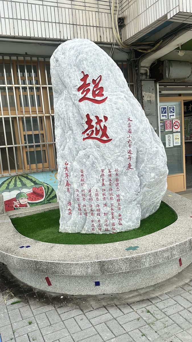 Large rock monument inscribed with 超越 (Excel) in the school courtyard