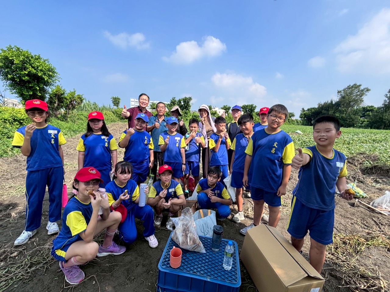Students in the field after digging sweet potatoes, giving a thumbs up