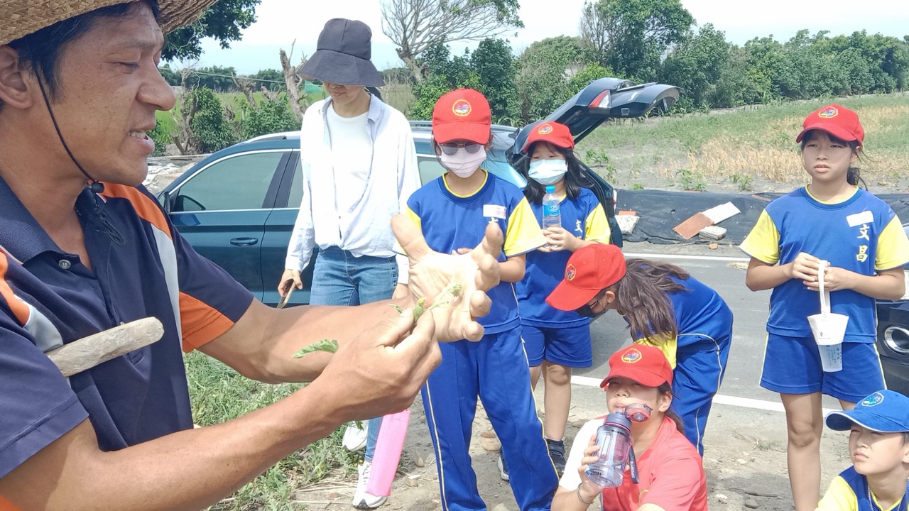 A local farmer showing crops to Wenchang students in the field