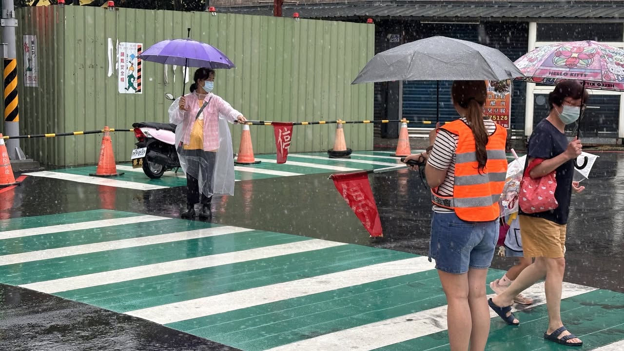 Crossing guard volunteers helping students cross the street in the rain