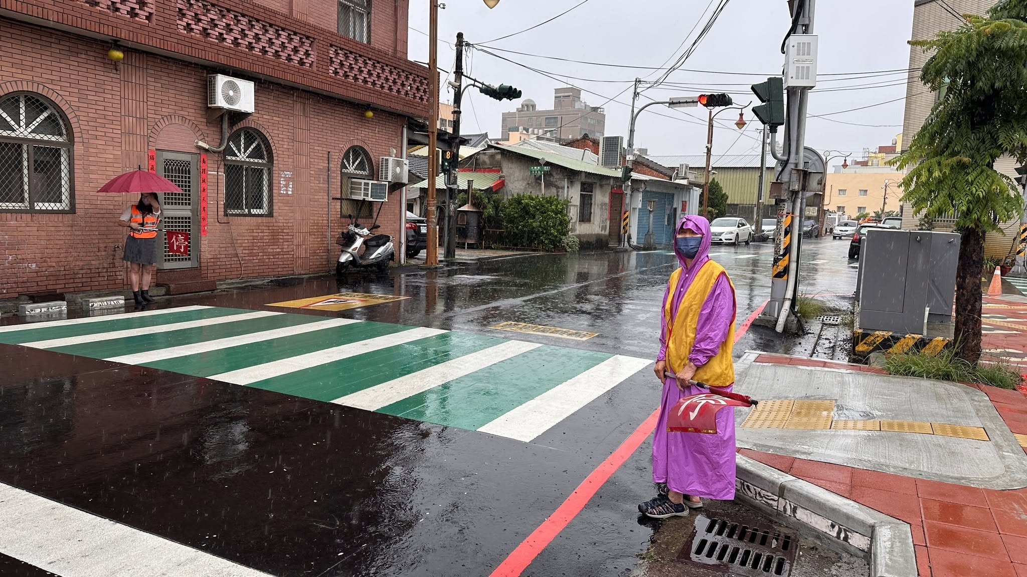 A Wenkai crossing guard volunteer standing watch in the rain