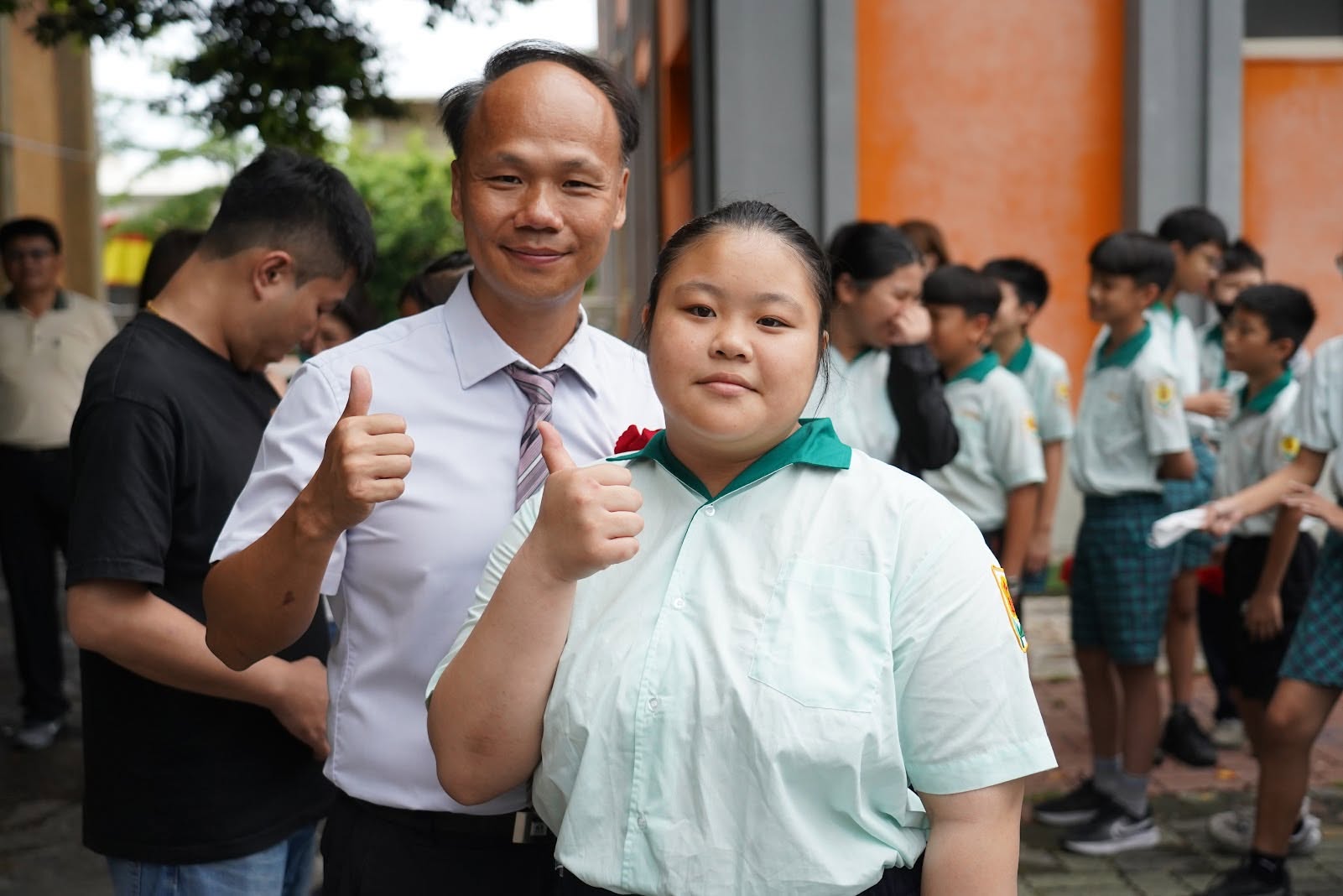 Principal Kuo posing with a graduate outside the school building