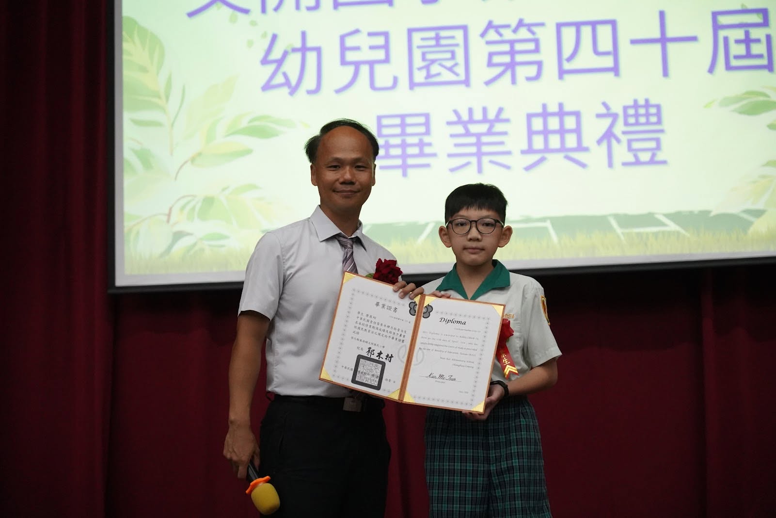 Principal Kuo presenting a diploma to a graduate on stage