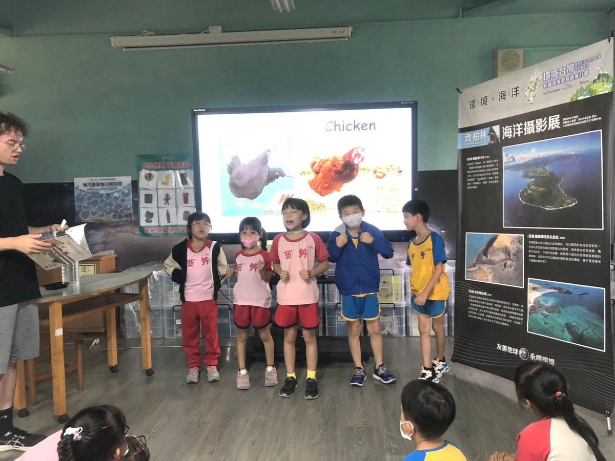學生站在螢幕前模仿小雞，螢幕上寫著 Chicken