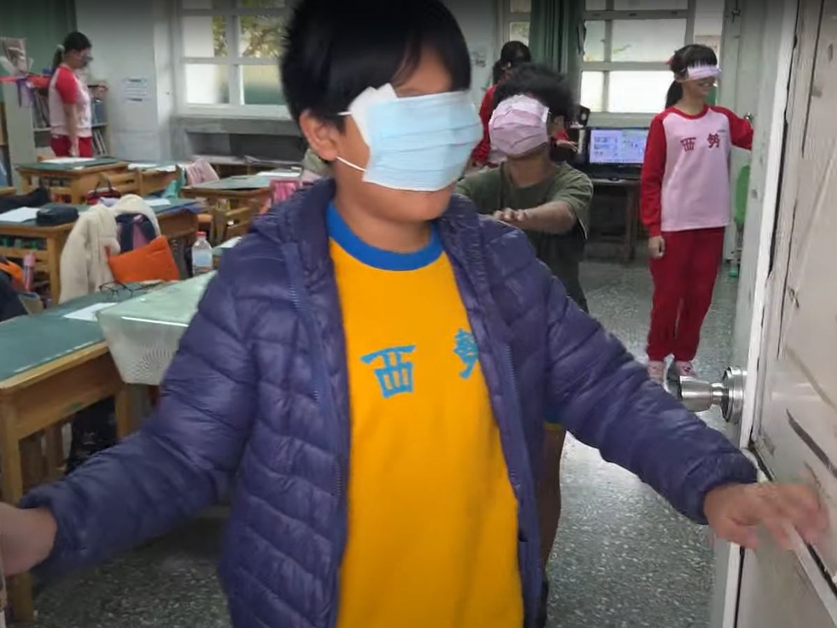 六年仁班學生用口罩遮住眼睛，用手摸著門體驗看不見的感覺