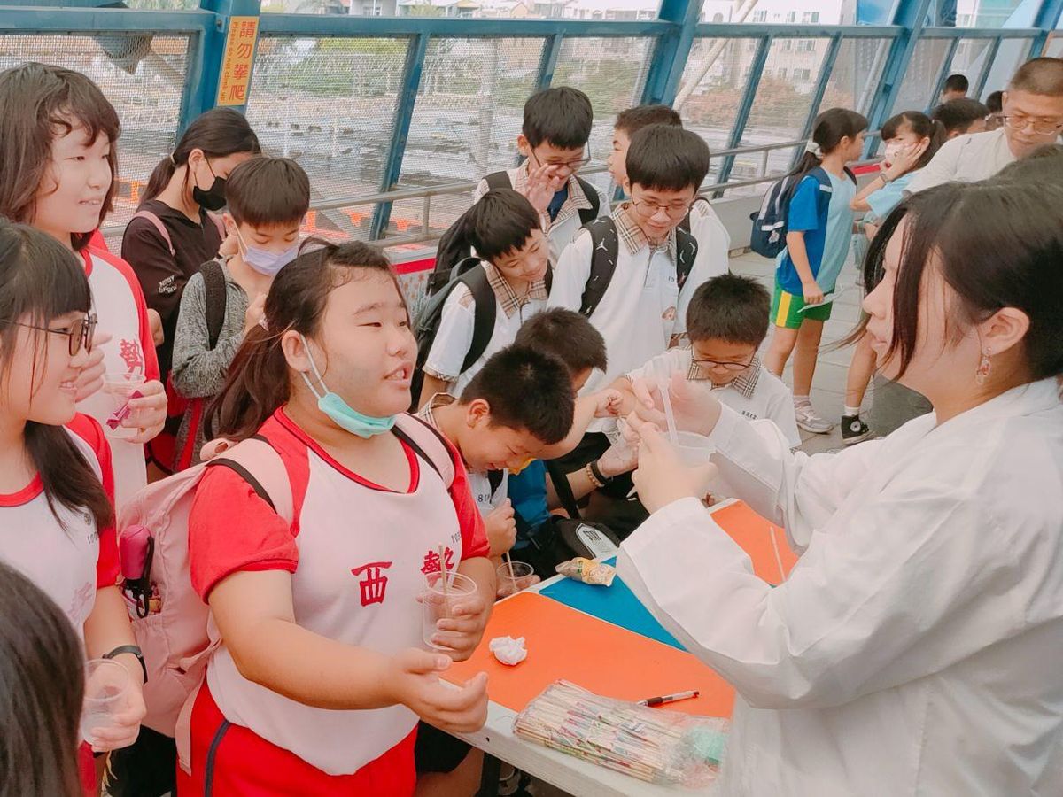 學生在彰化火車站前的科學闖關活動，看穿白袍的關主示範實驗