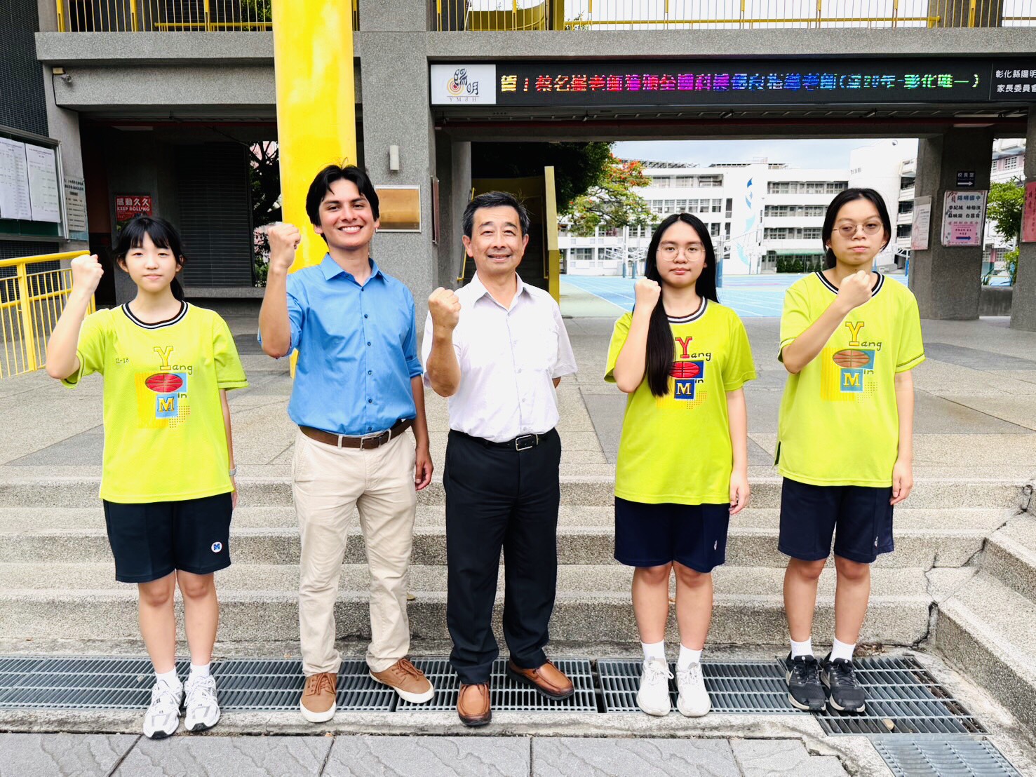 Teacher David Martinez with Principal and Yangming students at the school entrance, June 2026