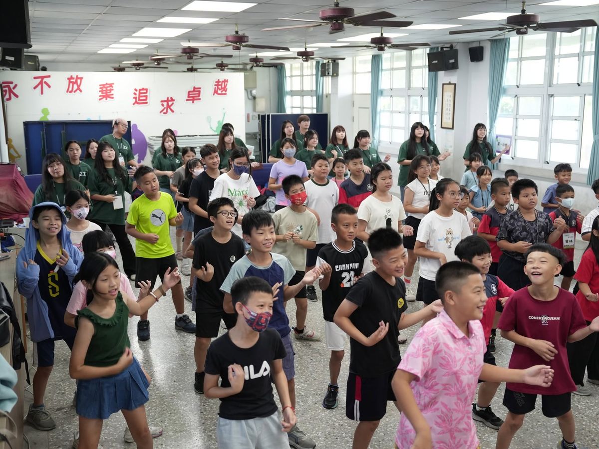 Children and university volunteers dance a warm-up together