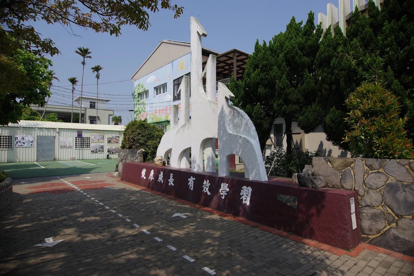 永豐國小入口意象白色人形雕塑，基座上寫著「健康成長　有效學習」 The white figure sculpture at the entrance, its base reading &lsquo;Grow up healthy, learn effectively&rsquo;