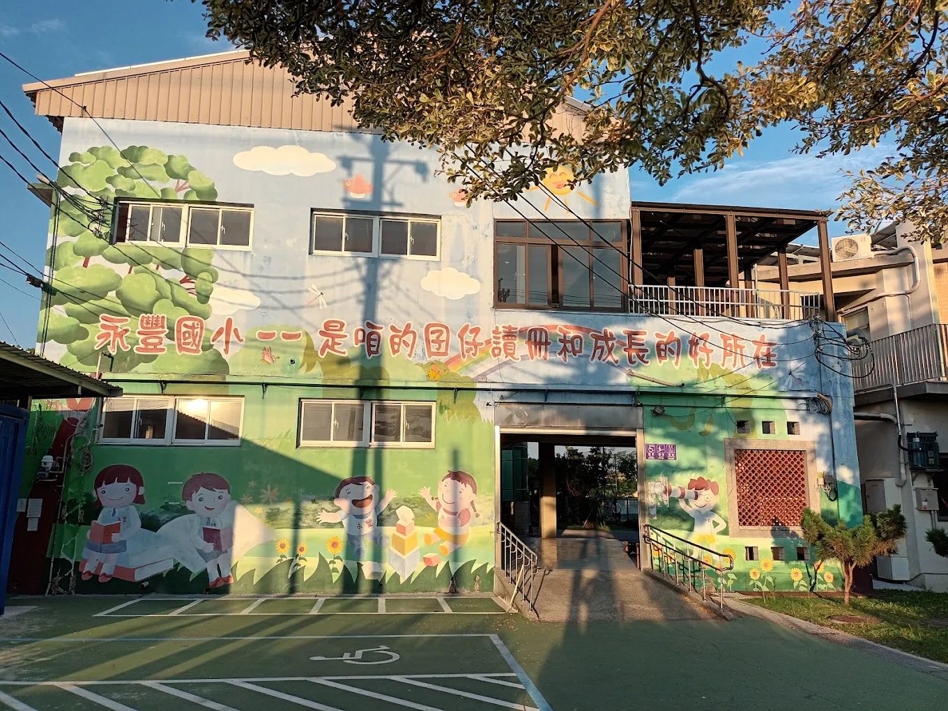 永豐國小教學樓的彩繪牆，寫著「永豐國小－－是咱的囝仔讀冊和成長的好所在」 A painted wall on a teaching block reading, in Taiwanese, &lsquo;Yongfeng Elementary — the good place where our children read and grow&rsquo;