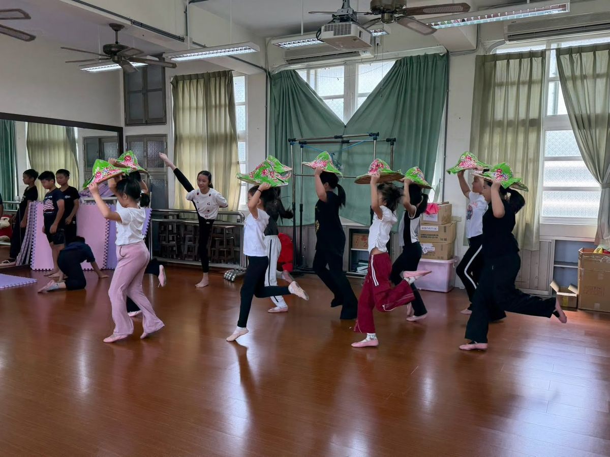 源泉國小舞蹈隊學生戴著客家花布斗笠，在舞蹈教室裡排練舞蹈動作 Yuanchyuan dance-team students in Hakka floral-cloth hats rehearsing in the dance studio