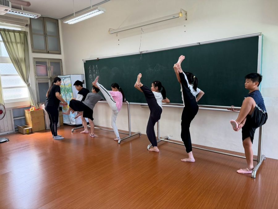 舞蹈隊學生在把桿邊做高踢腿與拉筋的基本功訓練 Dance-team students doing high kicks and stretches at the barre