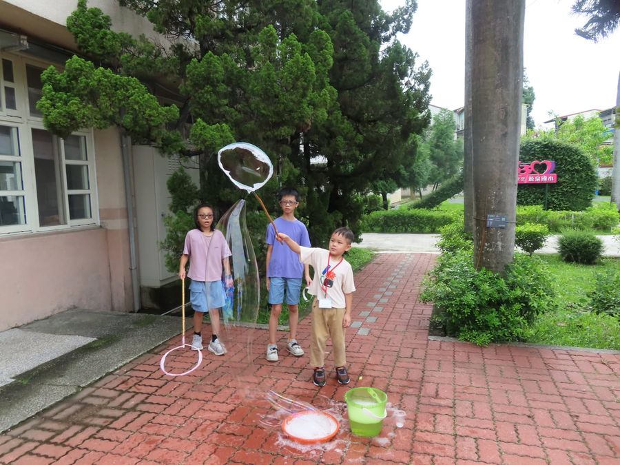 源泉國小學生在大樹下吹起巨大的泡泡，玩得很開心 Yuanchyuan children blowing giant bubbles under a big tree