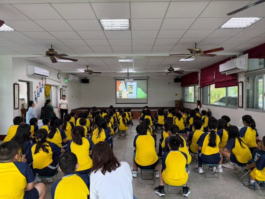 源泉國小學生坐在視聽教室裡，一起聆聽友善校園與安全宣導 Yuanchyuan students sitting together in the hall for the friendly-campus and safety talk
