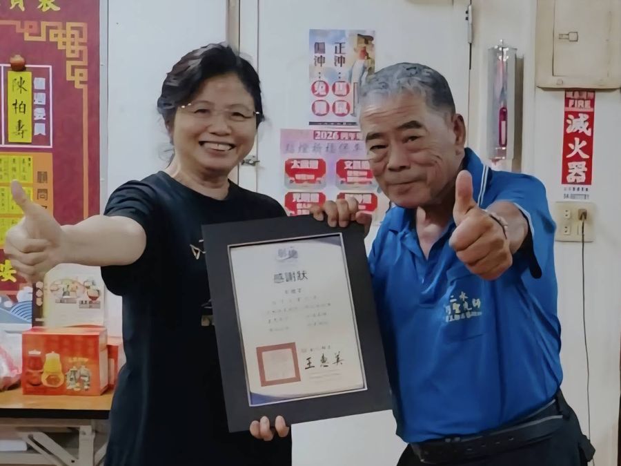 林淑貞校長與贊助單位代表比出大拇指，一起舉著縣府頒發的感謝狀 Principal Lin Shu-chen and a sponsor's representative giving a thumbs-up with the county's certificate of thanks