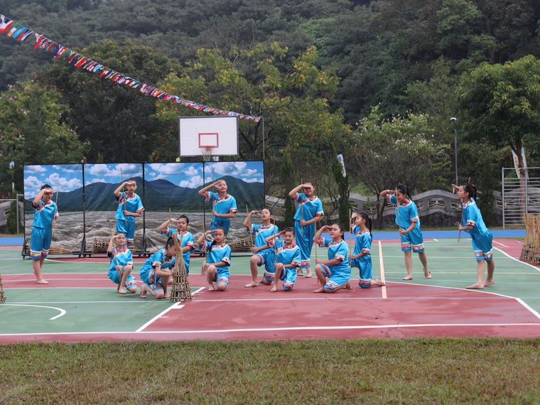 源泉國小民族舞蹈社學生穿著藍色舞衣，在戶外球場上表演 Yuanchyuan folk-dance club students performing in blue costumes on the outdoor court
