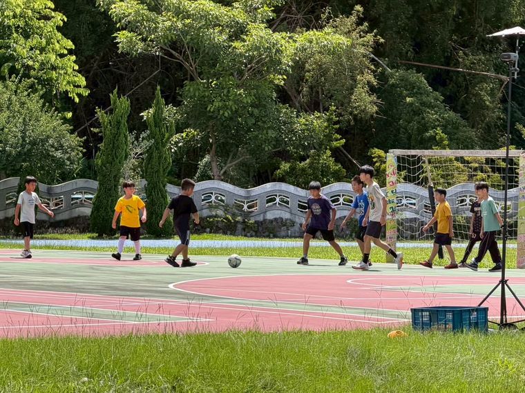源泉國小足球社學生在校園球場上練球，背景是綠樹 Yuanchyuan soccer club students at practice on the campus court