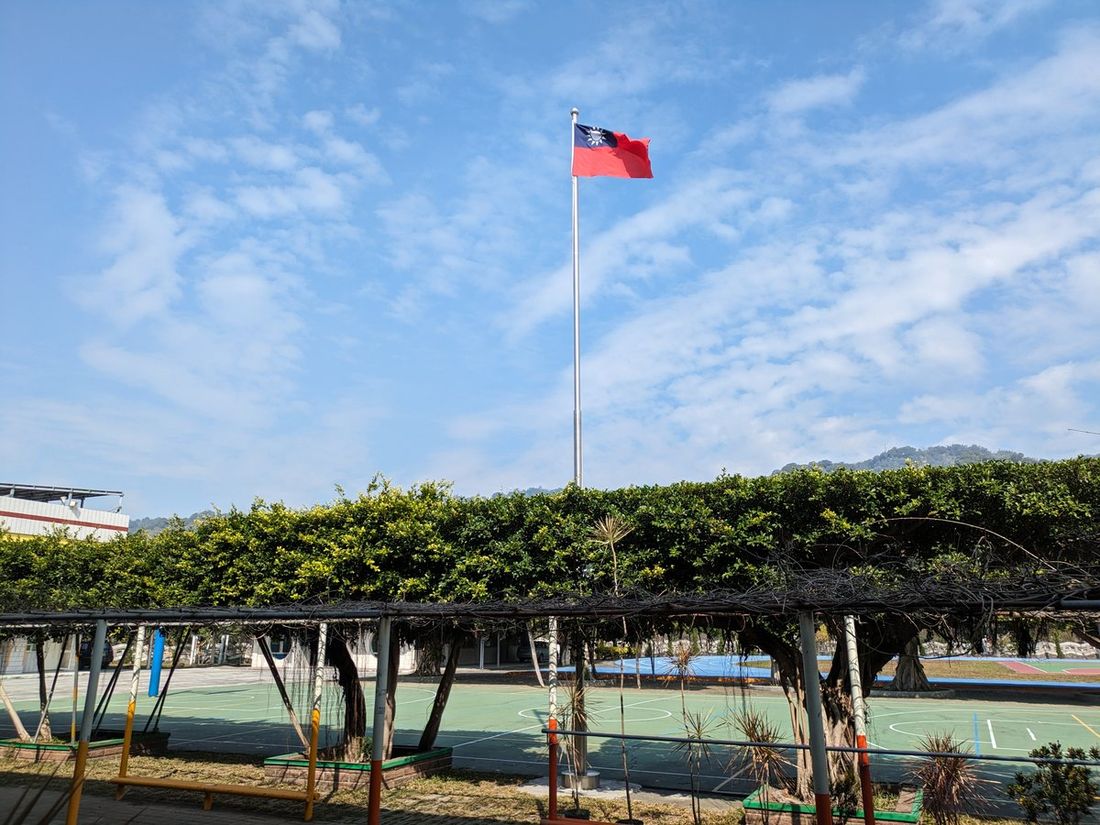 源泉國小的綠色棚架步道與國旗，遠處為八卦山脈 The green pergola walkway and flag at Yuanchyuan, the Baguashan hills in the distance