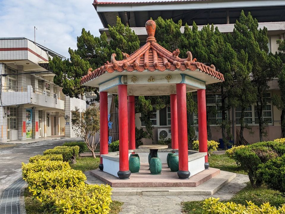 源泉國小校園裡的紅柱中式涼亭「中山亭」，四周有修剪整齊的綠籬 'Zhongshan Pavilion', a red-pillared Chinese pavilion in the Yuanchyuan grounds, ringed by clipped hedges