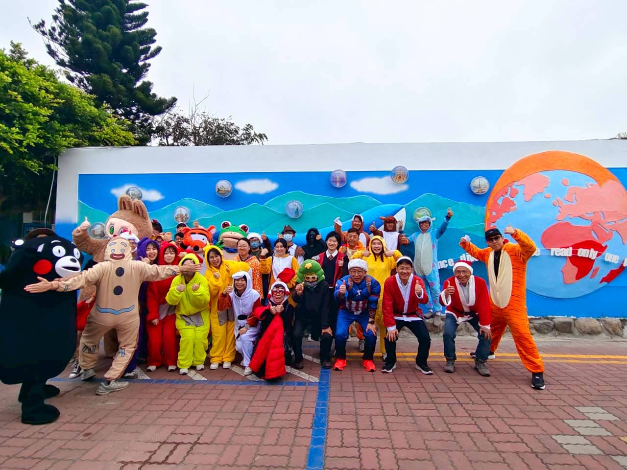 Yuhua students costumed in front of a colorful world-map mural