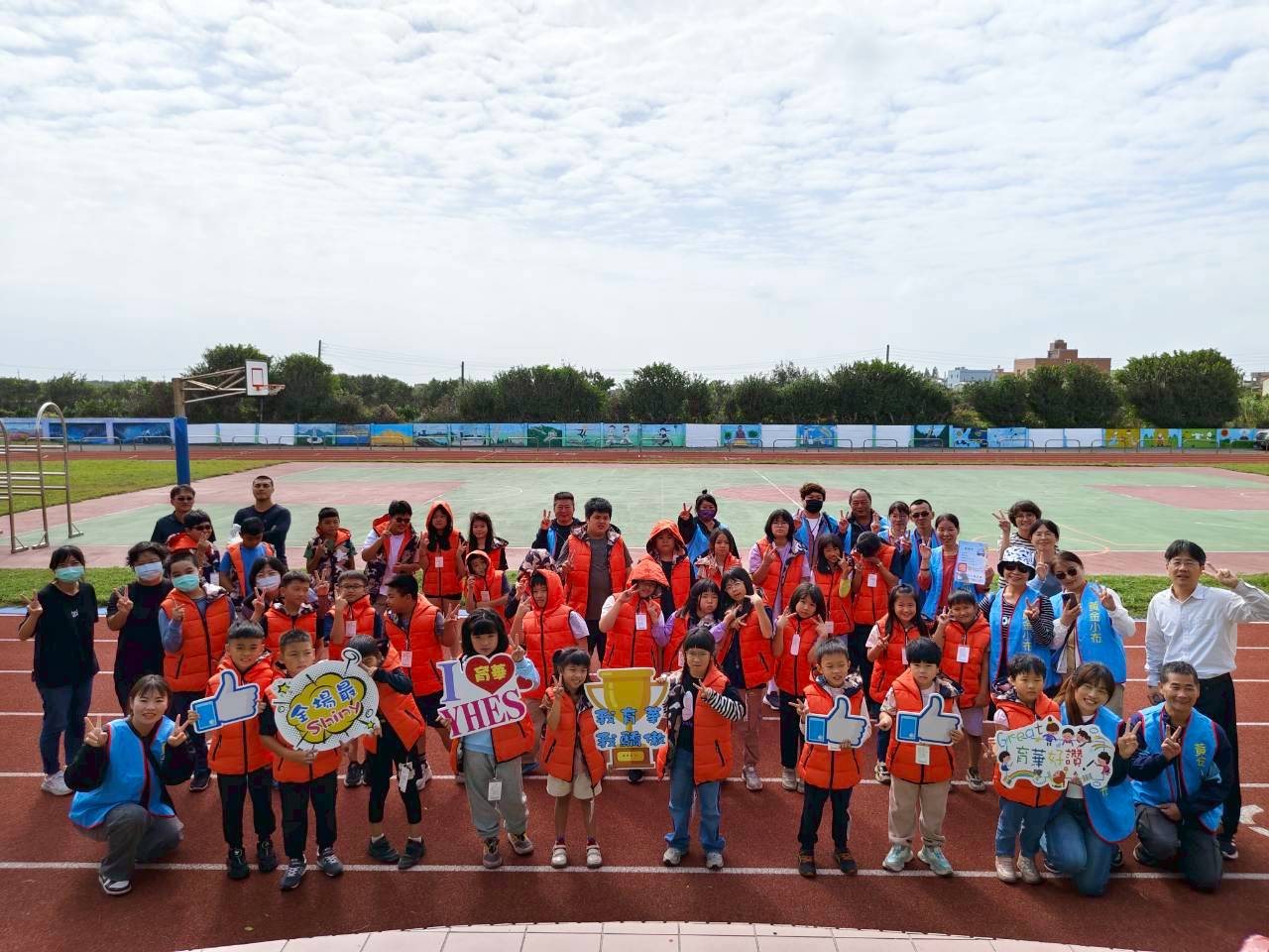 Yuhua students on the running track holding I-love-YHES placards and the character-education trophy