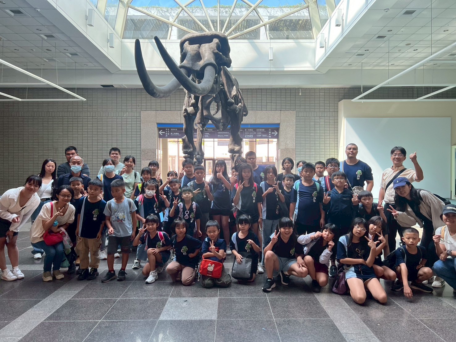 Yuhua students at the National Museum of Natural Science with a dinosaur skeleton