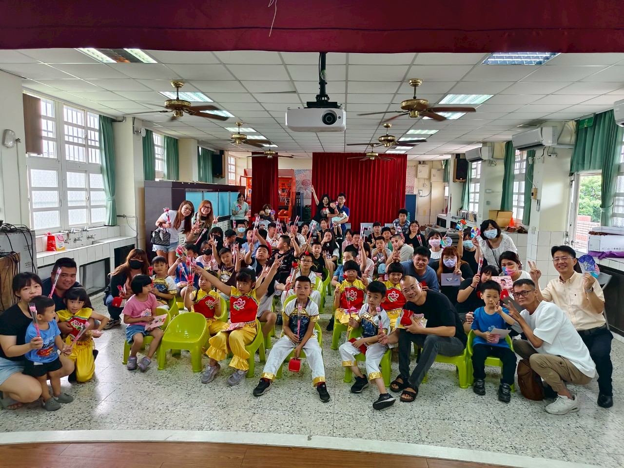 Yuhua students seated in a classroom for a school event, all giving a peace sign