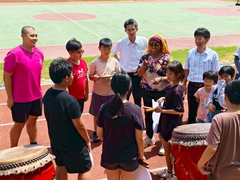 Dom Jones and the school principal gather in a circle with the student drummers on the running track