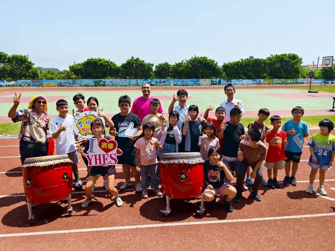 A large group of Yuhua students and teachers with the taiko drums on the running track