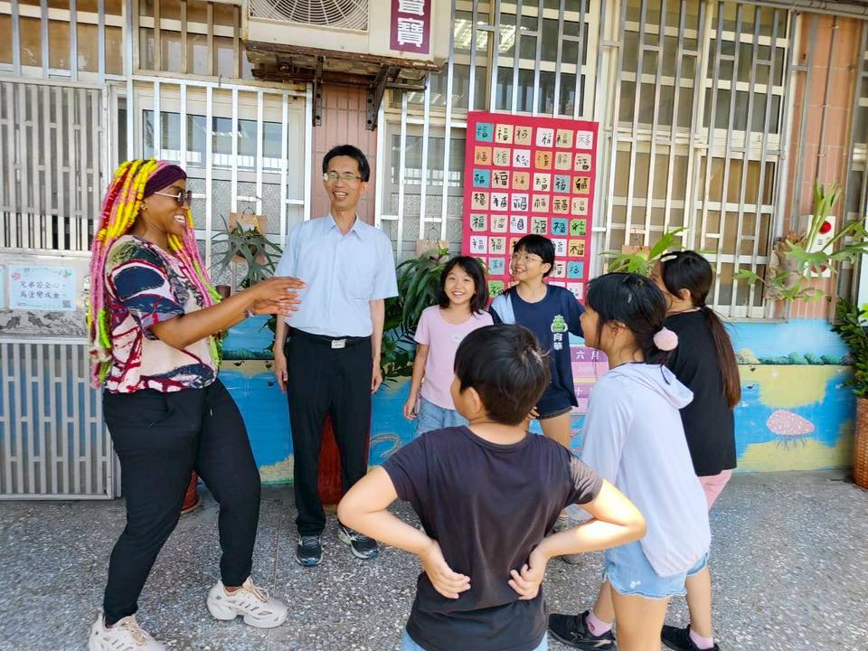 Dom Jones talking and playing a warm-up game with students in front of a wall of red fu calligraphy cards