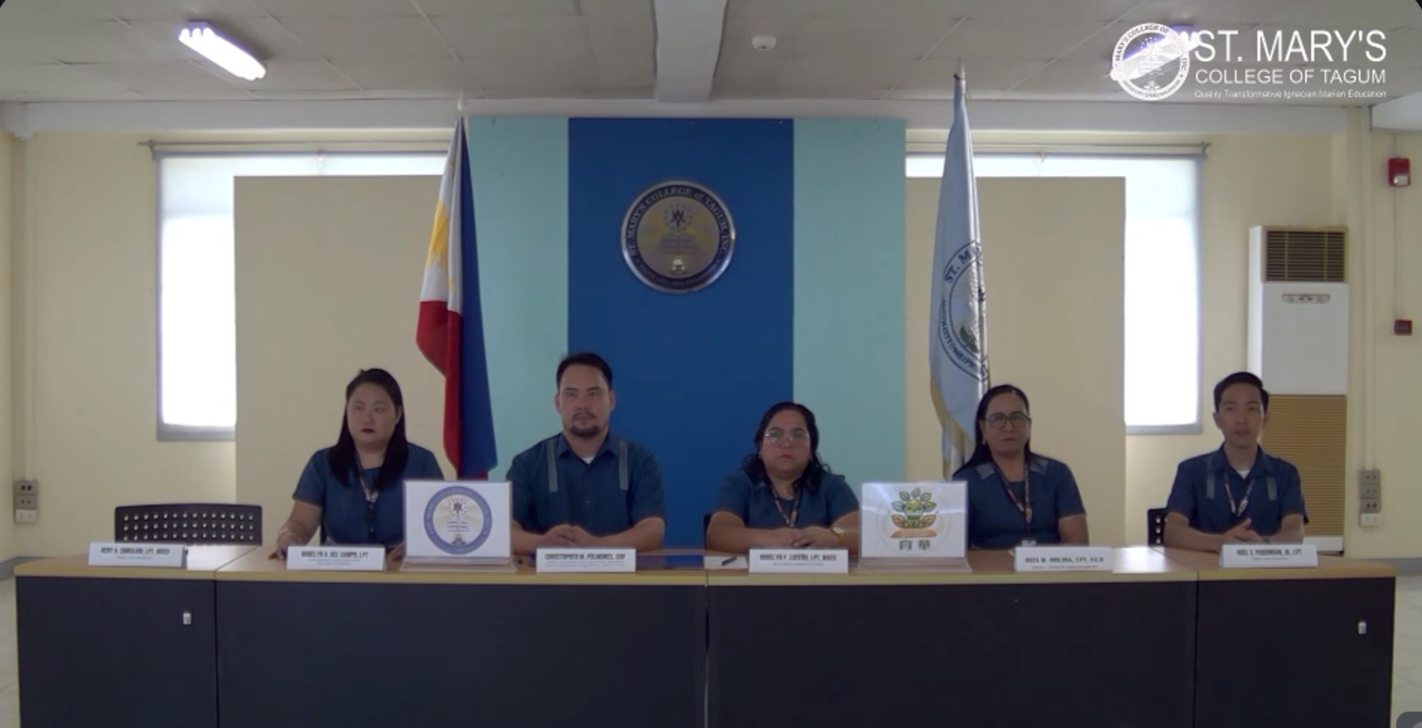 The St. Mary's College of Tagum delegation seated at the ceremony table with the Philippine flag and the school crest behind them